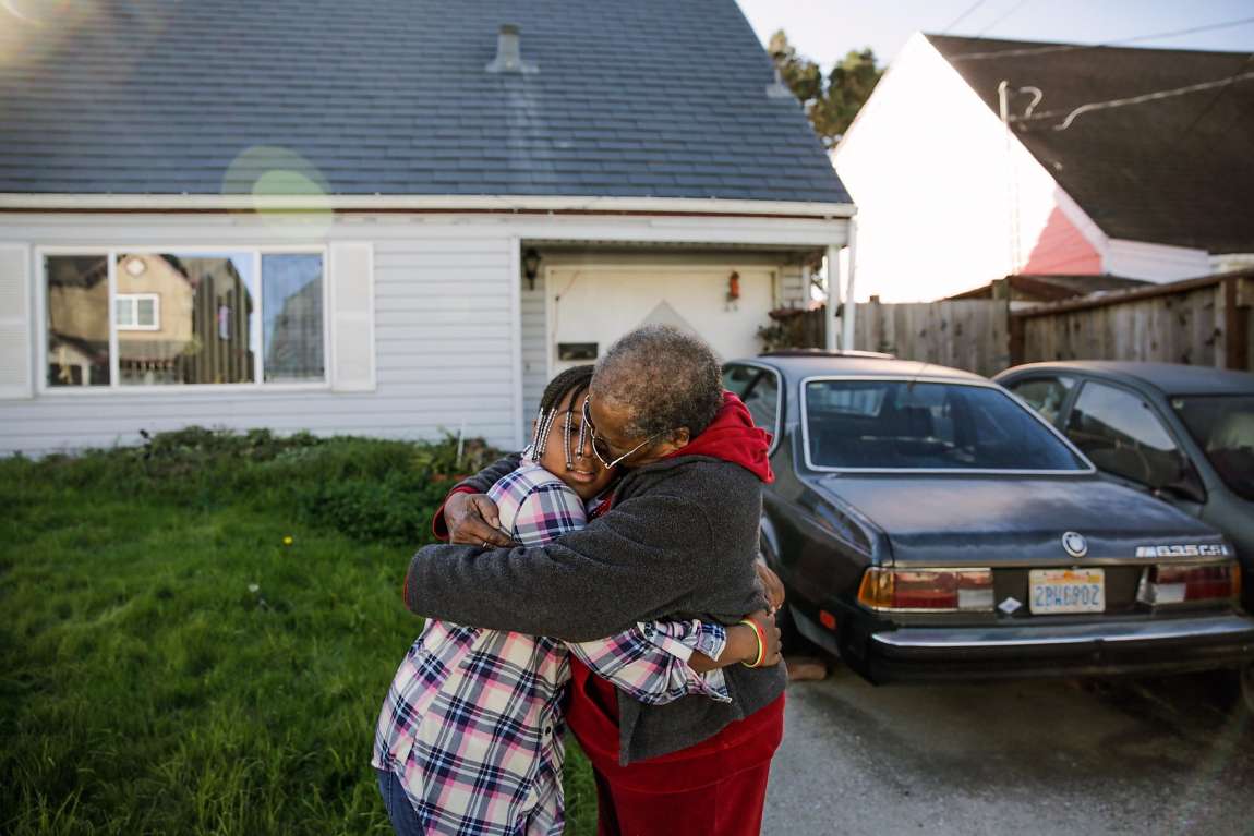 Woman embracing a child outside a home.