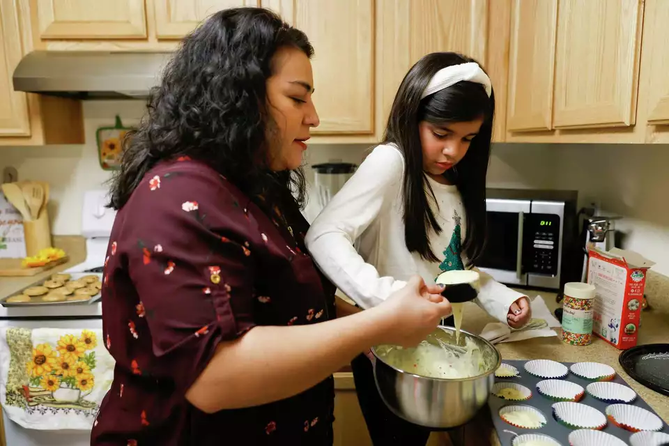 A woman and child baking cupcakes in kitchen—portraying learning and early childhood care.