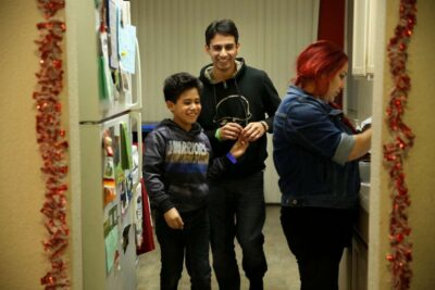 Father smiles with son in kitchen of apartment.