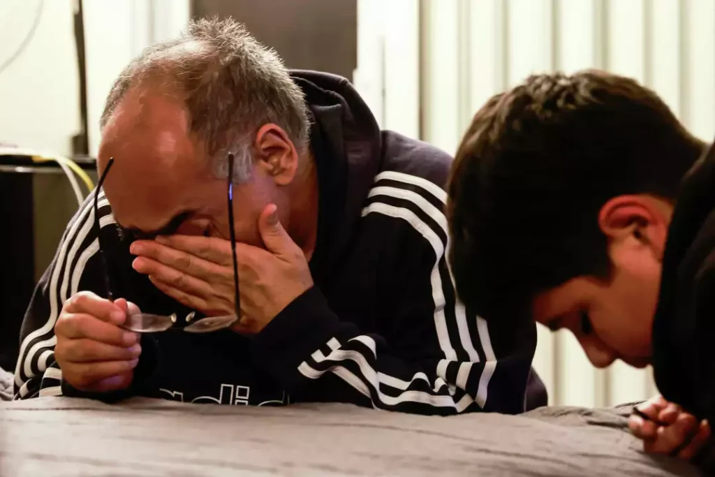 A man breaks down in tears while praying with someone beside him—expressing deep emotion in an intimate moment.