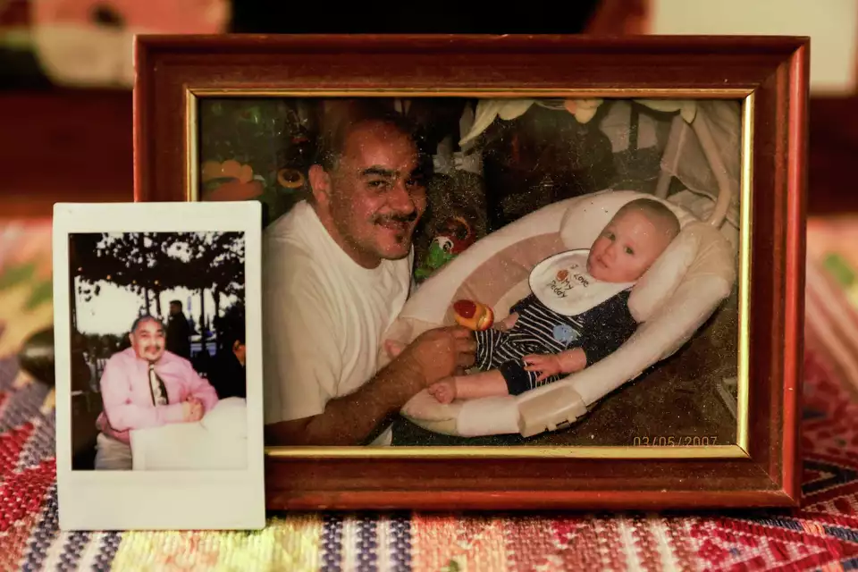 Framed photograph of a smiling man holding a baby, surrounded by other family pictures—evoking memories and legacy.