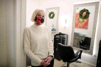 Woman wearing a mask stands in a salon setting.