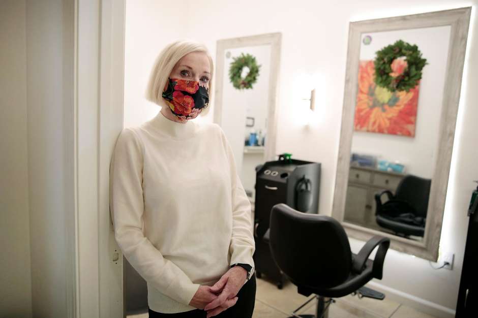 Woman wearing a mask stands in a salon setting.