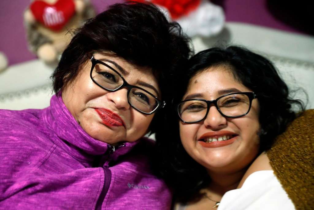 Mother and daughter smiling warmly together in matching glasses.