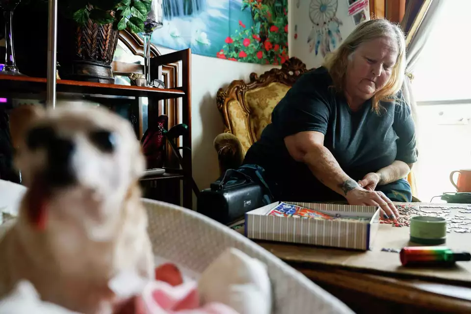 A woman works on a colorful jigsaw puzzle at home with small dog nearby—illustrating mindfulness and connection.