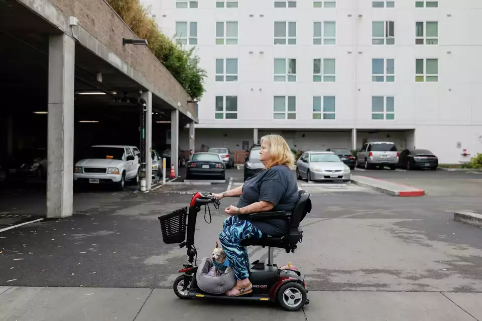 A person in a power wheelchair navigates a parking lot independently—demonstrating mobility and autonomy.