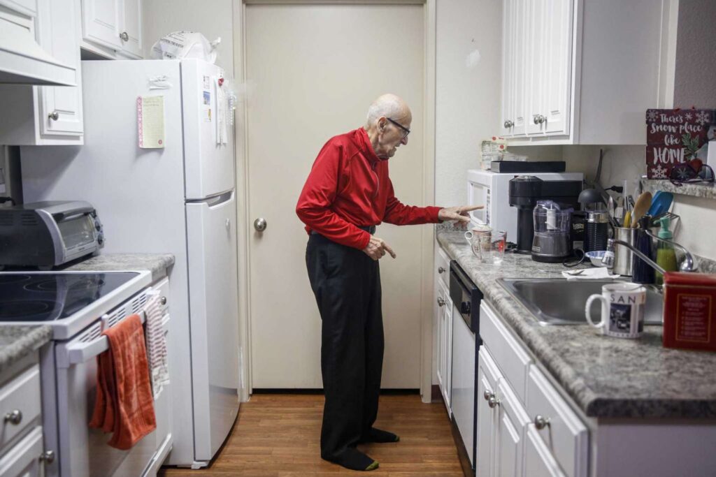 An older man prepares coffee in modest kitchen—symbolizing routine and home.