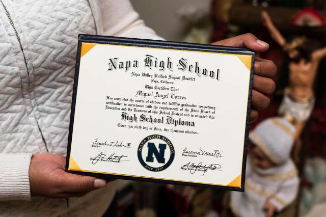 Close up of woman holding son's high school diploma.