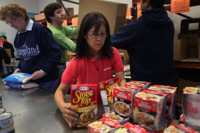 Volunteer sorts donated groceries at food bank.