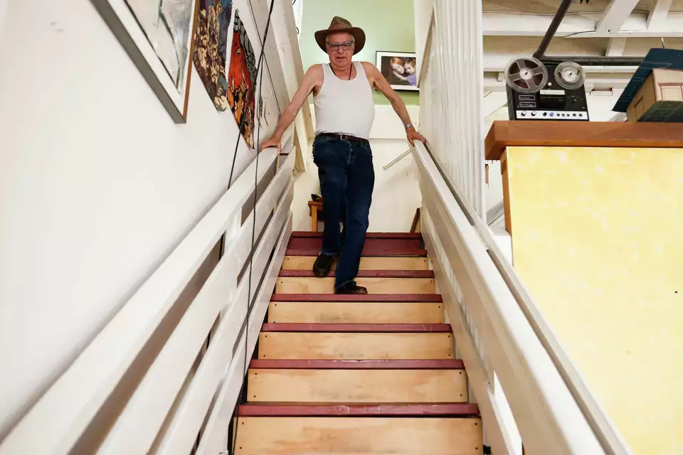 A man descends a staircase in a home lined with framed photos—symbolizing personal journey and rootedness.