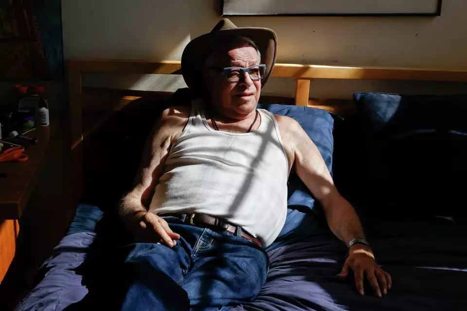 A man sits upright in bed—symbolizing comfort at home.