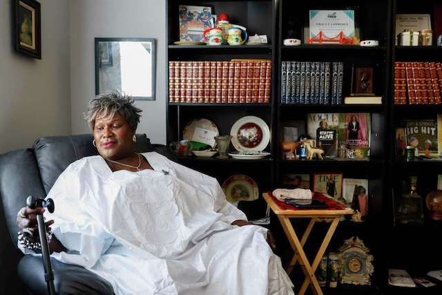 A woman sits in recliner chair in front of bookshelf—showing serenity and daily care.