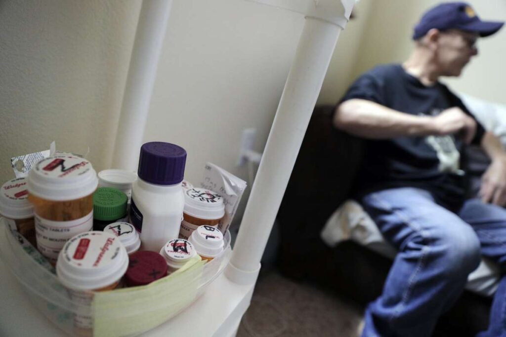 Elderly man sitting on couch next to medication.
