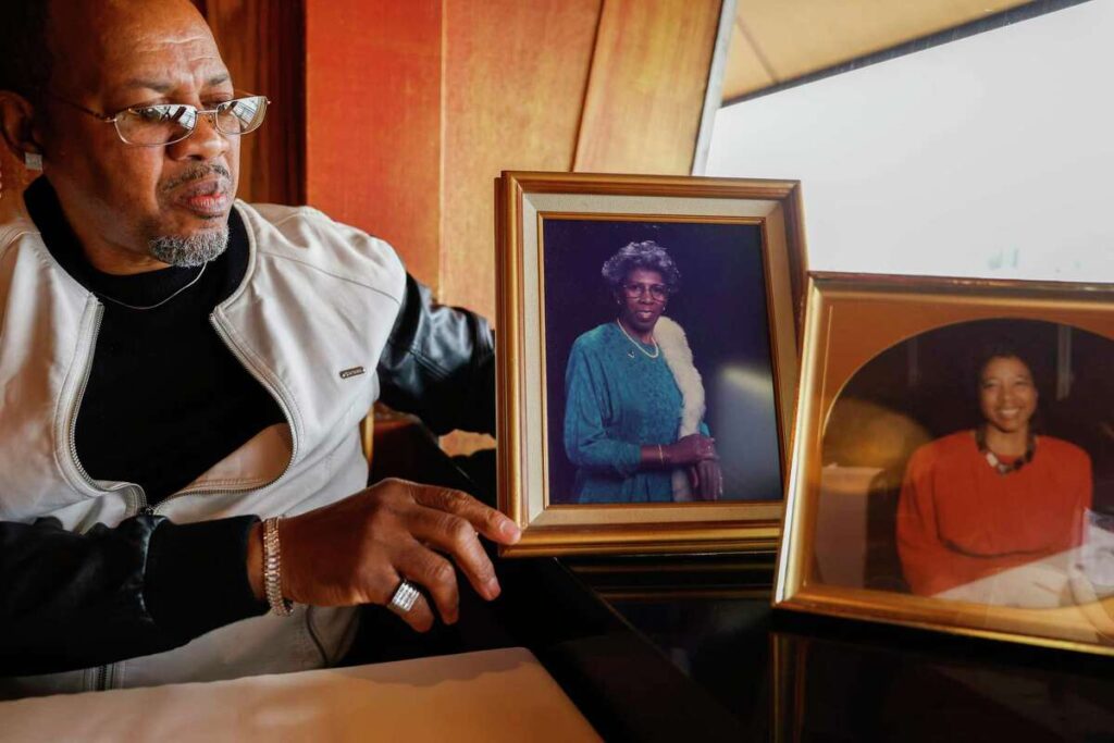 An elderly man holds a framed photo of his mother—honoring legacy and memory.