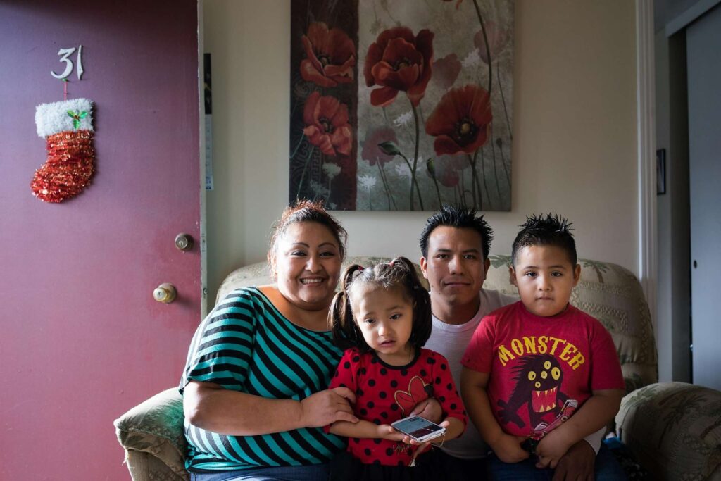 Family poses for photo in modest living room.