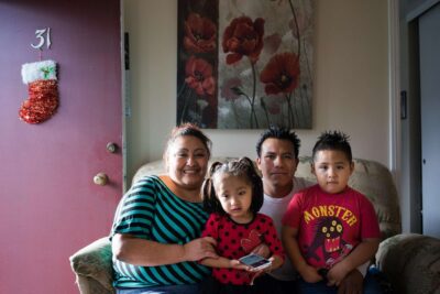 Family poses for photo in modest living room.
