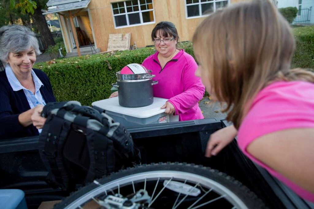 Family moves household items into new home while smiling.
