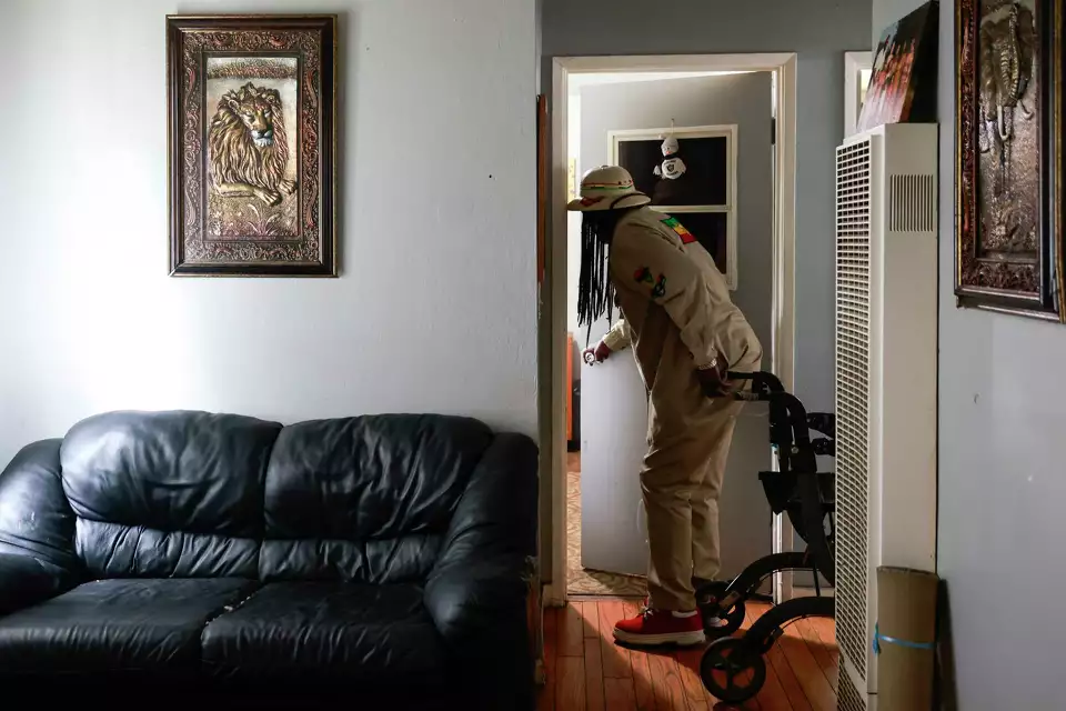 An older man reaches into a room from a hallway—implying care or checking in on someone.