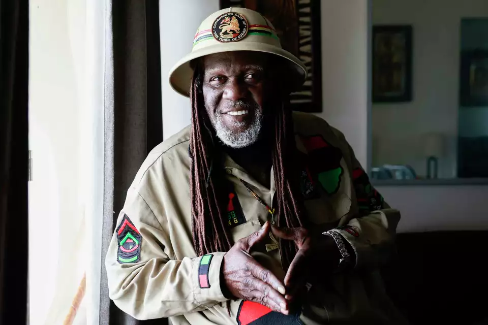 A smiling man in a wide-brimmed hat and scout uniform poses in a room—suggesting leadership and heritage.