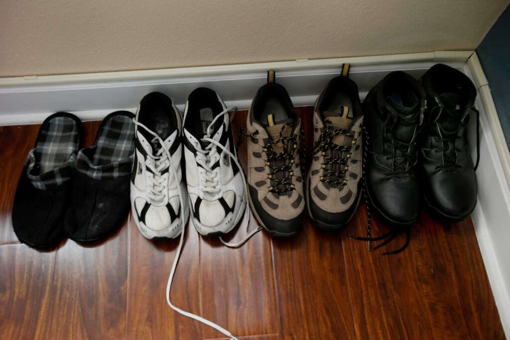 Four pairs of shoes lined up neatly on wooden floor.
