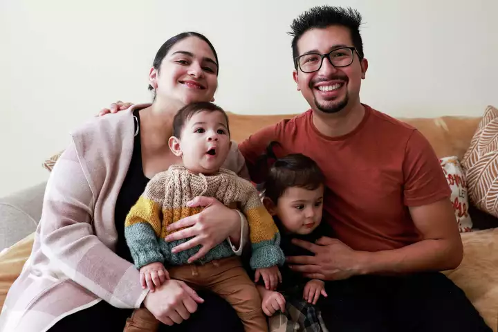 A young family of four smiles for a portrait—conveying unity and happiness.
