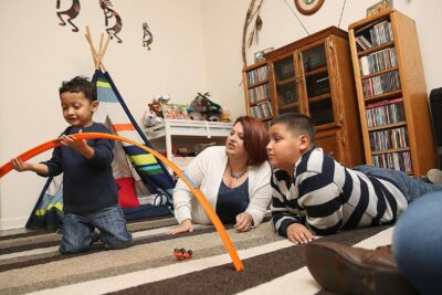 Mother and two children play on floor of living room.