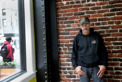 Man stands against brick wall for photo.