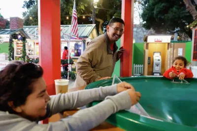A family enjoys an evening out at a fair, surrounded by lights and games—capturing joy and togetherness.