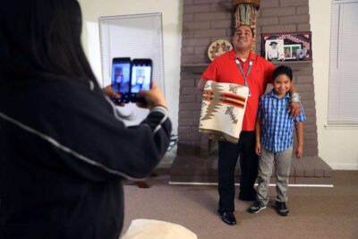 Father poses with son in living room for a photo.