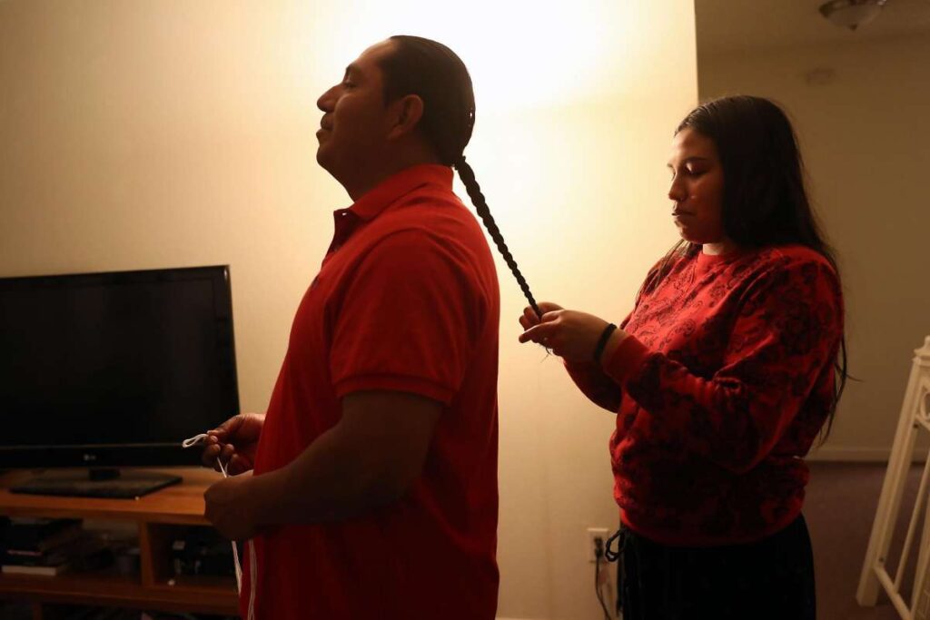 Man getting hair braided by woman.