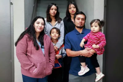 Parents with their four children stand close together, smiling warmly—demonstrating unity and family connection.