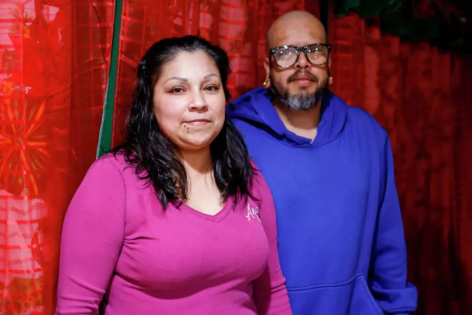 A woman and man stand closely together, smiling in front of a red curtain—emphasizing unity and strength.