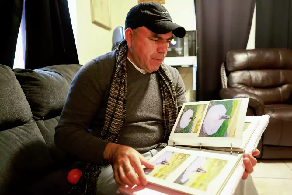 Man sitting on a couch viewing a photo album, reflecting on personal memories.