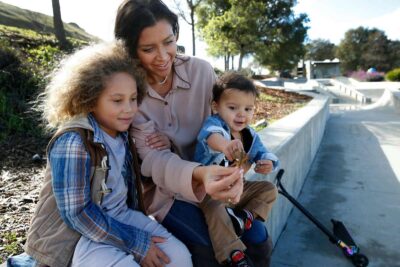 Mother sitting on a bench with two children outdoors.