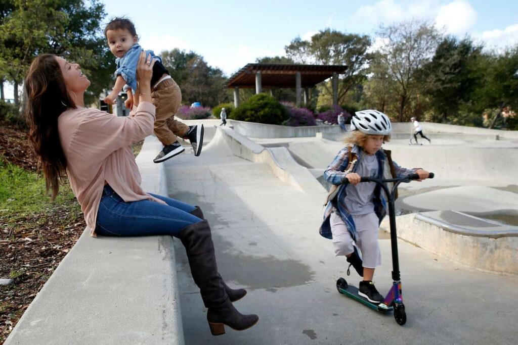 Family riding scooters together at a skate park.