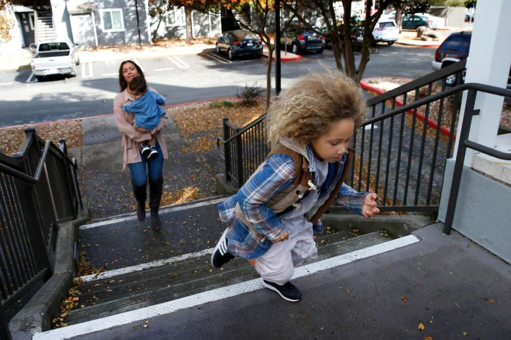 Young girl running up stairs as others look on.