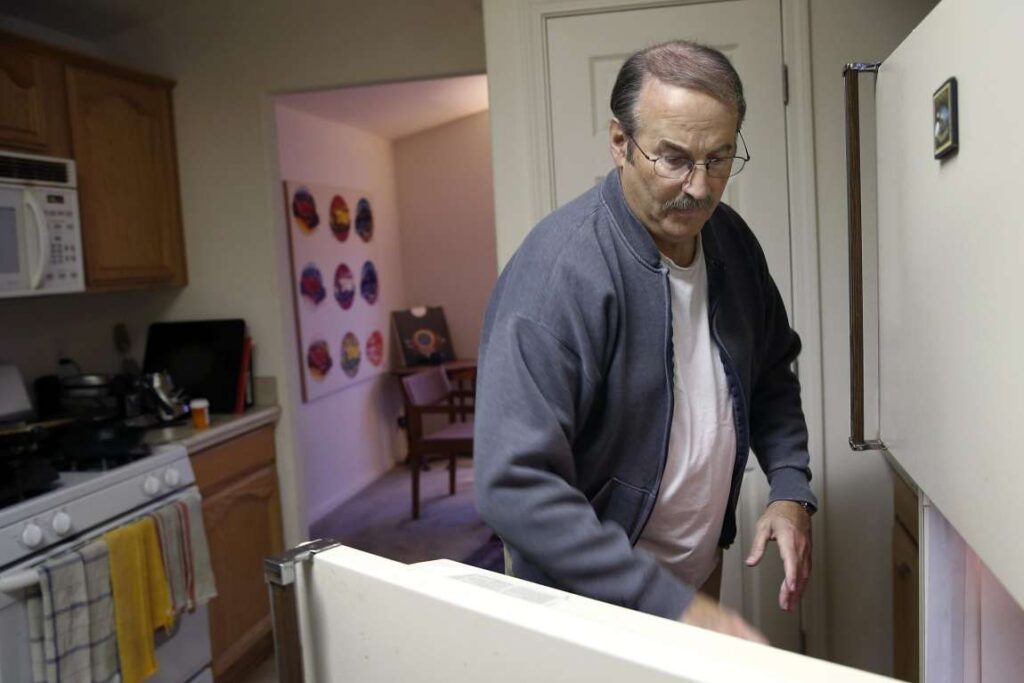 Man opening refrigerator in kitchen.