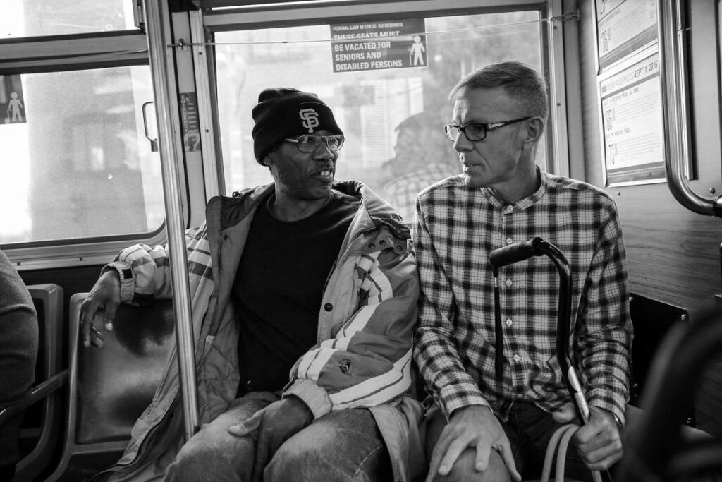 Two men sitting side by side on a public bus.