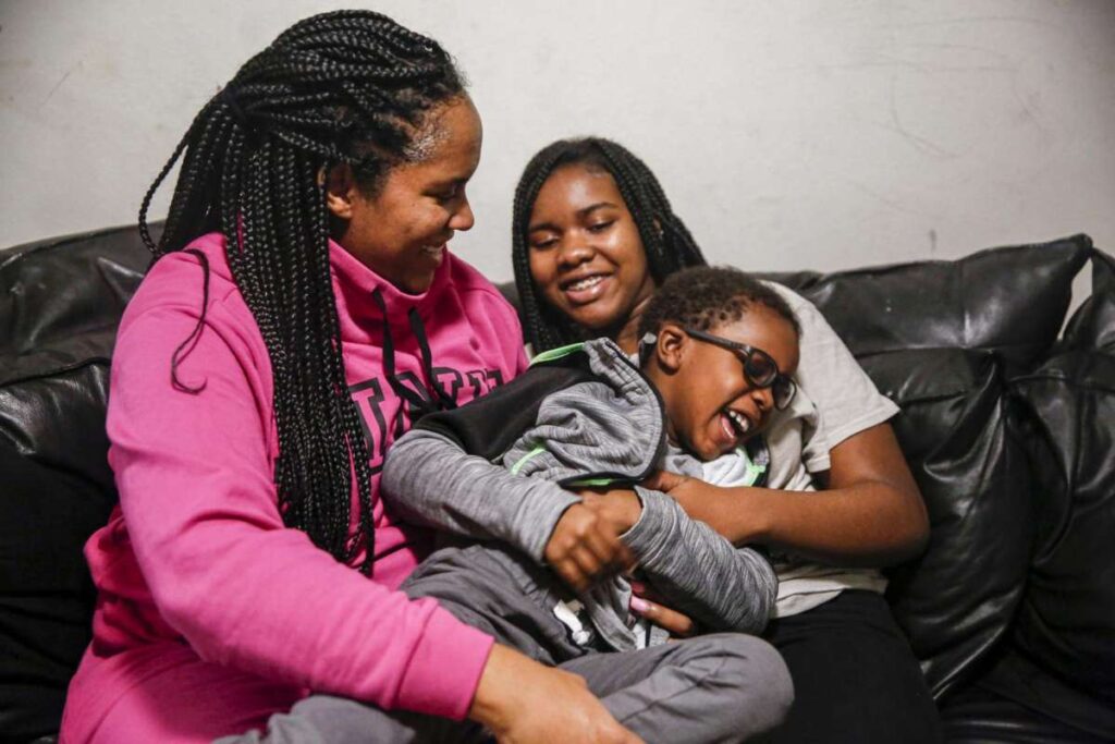 A mother and two children sit together on a couch, smiling and embracing—illustrating love and generational connection.