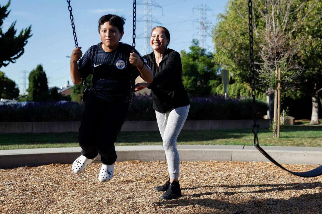 A woman and child on swing set in a park—portraying play, exercise, and connection.