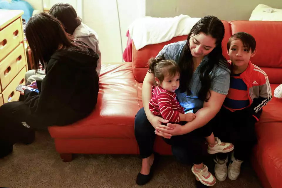 A mother sitting on a couch with a young children, sharing a moment of comfort and care in a home setting.