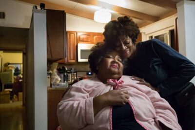 Two family members embrace in living room.