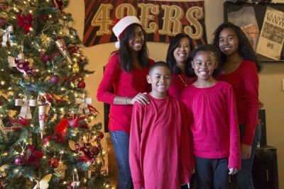 Family poses for portrait near Christmas tree.