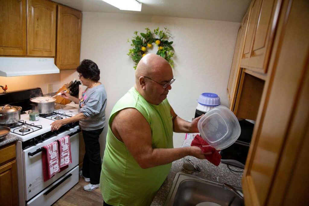 Couple prepares meal in modest kitchen.