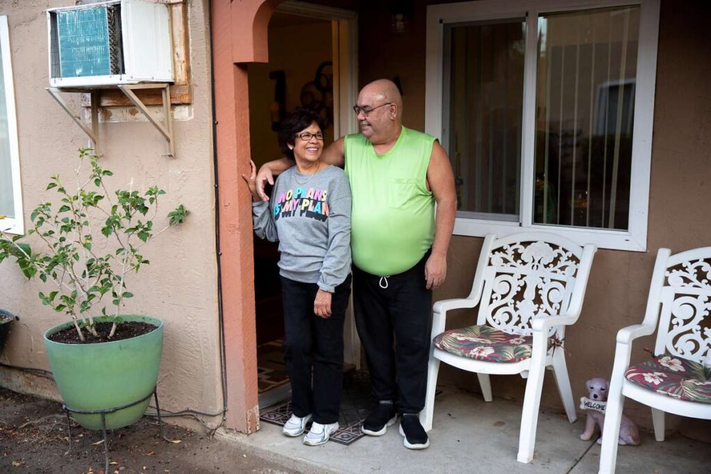 Couple standing outside apartment.