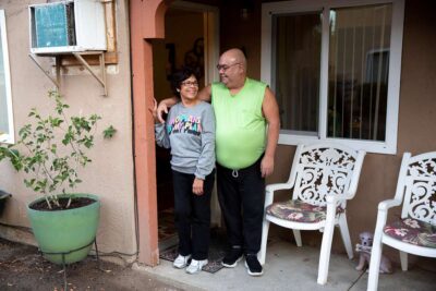 Couple standing outside apartment.