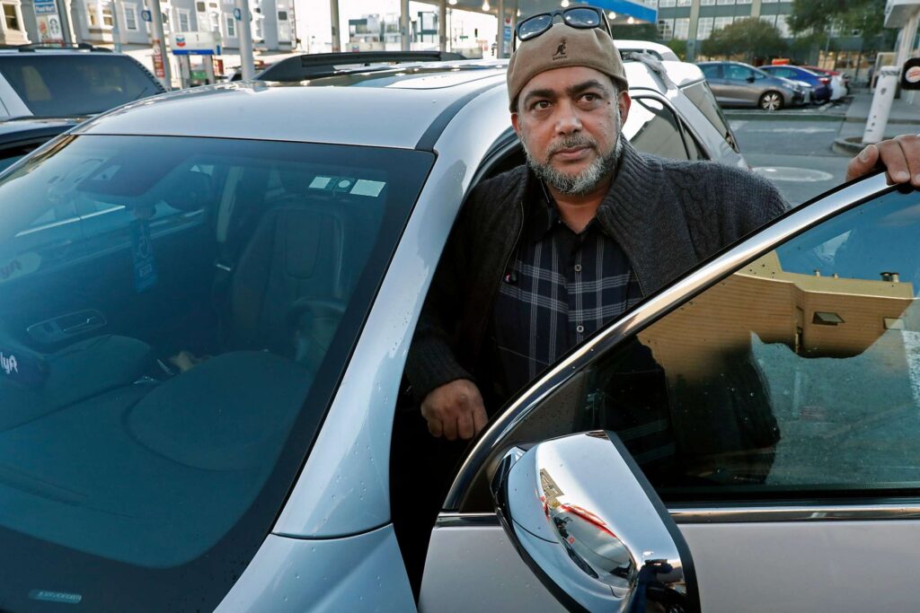 Man sitting in a car looking out the window with a serious expression.