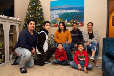 Family gathered in front of a Christmas tree, smiling for a group photo.