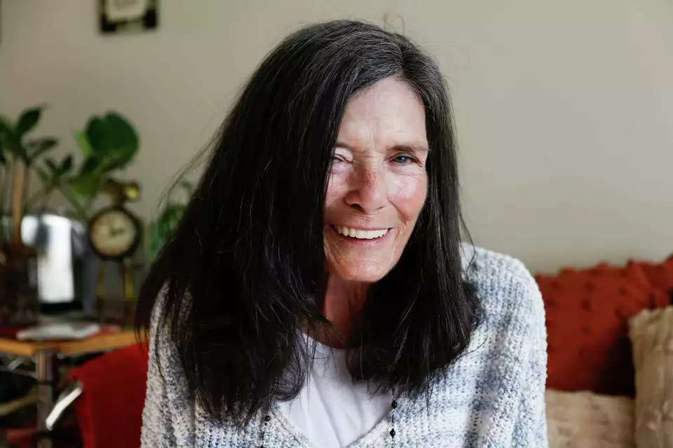 A woman with long dark hair smiles warmly in a bright room—capturing authenticity and approachability.