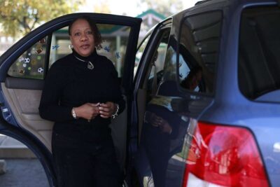 Woman poses for photo standing outside car.